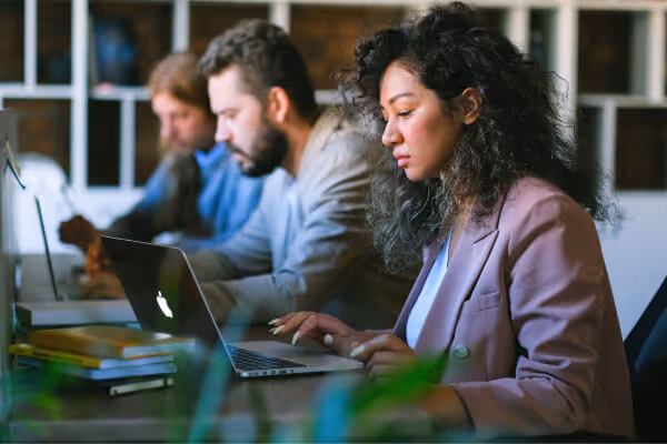 Marketing professionals working on laptops in a modern office.